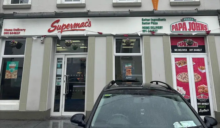 Supermac's and Papa John's restaurant exterior in Athenry, Ireland. Features a traditional building facade, prominent