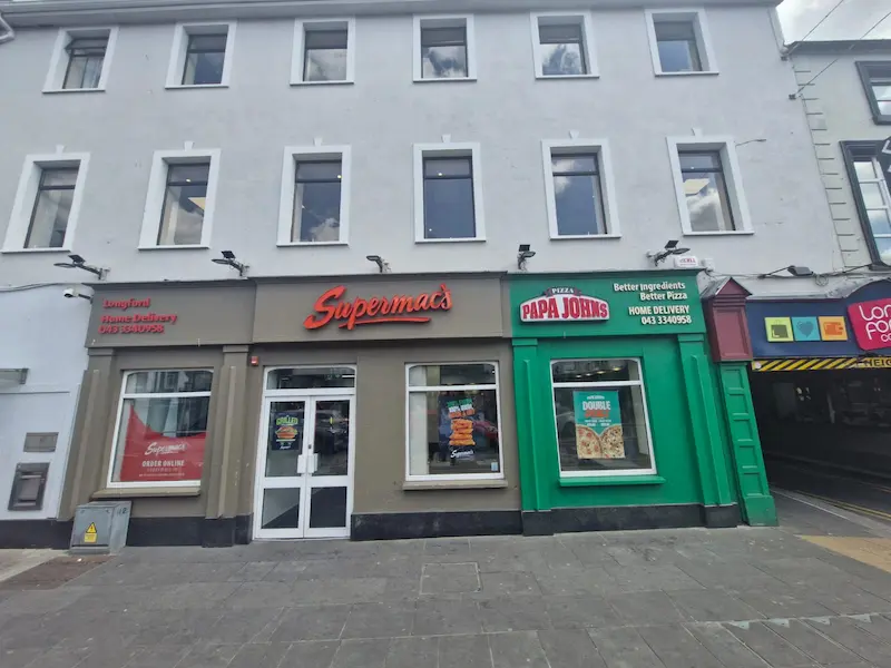 Supermac's and Papa John's restaurant exterior in Longford, Ireland. Features a two-toned facade (grey and green), prominent 