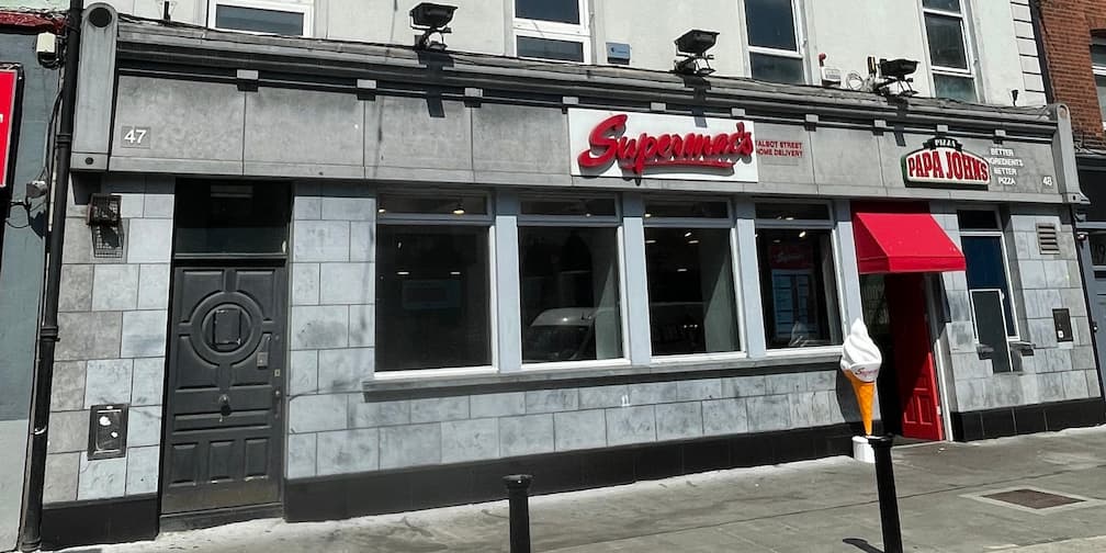 Supermac's and Papa John's restaurant exterior on Talbot Street, Dublin, Ireland. Features a grey stone facade, prominent 